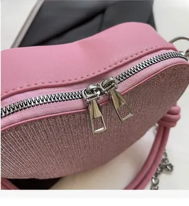 Detail of smooth metal double zippers on a pink heart-shaped sequin crossbody bag