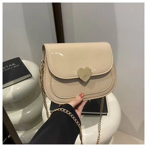Detailansicht beige Lackleder-Umhängetasche mit herzförmigem goldfarbenem Metallverschluss