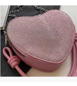 Close-up of pink heart-shaped bag with glitter fabric and metallic chain strap detail