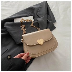 Detailansicht der beigen Lackledertasche mit goldenem Herzverschluss und eleganter Kette