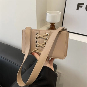 Sac à bandoulière beige minimaliste avec détails de laçage et œillets argentés