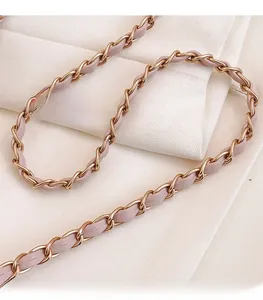 Dettaglio della tracolla in pelle rosa chiaro e catena in metallo oro per borsa