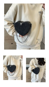 Detail of heart-shaped crossbody bag with black sequins and silver chain strap