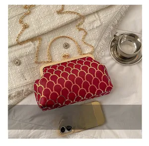 Detail of red sequin evening bag with gold fish scale pattern and metal chain strap