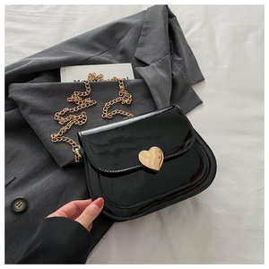 Detailansicht der schwarzen Lackledertasche mit einer goldenen herzförmigen Metallschnalle