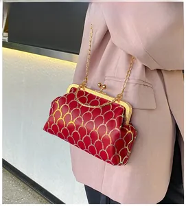 Detail of red evening bag with golden sequins worn by a model in a pink suit jacket