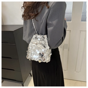 Detail shot of a silver sequin bucket bag featuring a sleek metallic chain strap