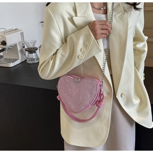 Detail of pink heart-shaped sequin crossbody bag with elegant silver chain shoulder strap