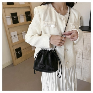 Dettaglio elegante borsa a secchiello nera con coulisse, catena e etichetta fashion
