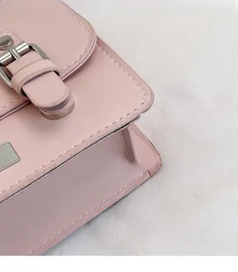 Detail of pink crossbody bag with cross-grain texture and silver metal buckle closure