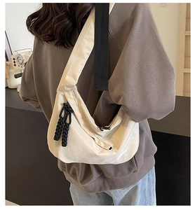 Detailed view of beige nylon crescent bag with adjustable strap and woven zipper pullers