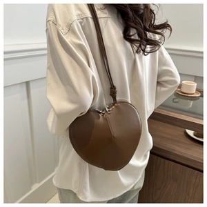 Chic brown heart-shaped leather crossbody bag shown on model for size and style reference