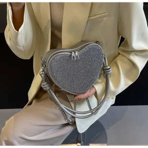 Detail of silver heart-shaped bag with sparkling sequins and woven knot handle