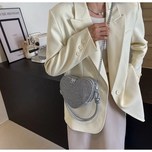 Detail of silver heart-shaped sequin bag with chain strap shown in a lifestyle setting