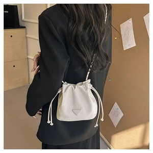 Dettaglio borsa a secchiello in camoscio beige con tracolla a catena dorata e logo