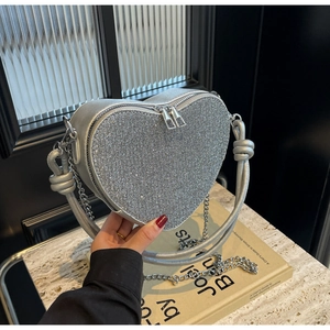 Detailed macro view of heart-shaped silver sequin bag with double zipper and chain strap