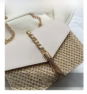 Detail showing the straw texture and gold chain tassel of the woven crossbody beach bag