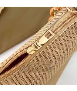 Detailed close-up of woven bag featuring golden metal zipper and orange resin chain link