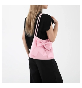 Détail latéral du sac cabas rose avec un grand nœud en cuir mat et de fines brides