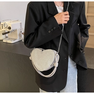 Detail of a heart-shaped crossbody bag with silver sequins and stylish chain strap