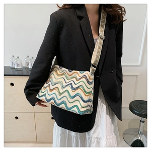 Detail of multi-color wavy knit tote bag with wide jacquard strap on a model