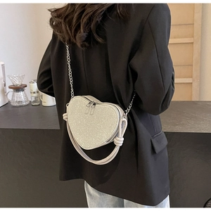Close-up of heart-shaped silver sequin crossbody bag with chain and leather straps