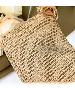 Close-up of beige woven crescent bag texture with resin ring and metallic hardware details