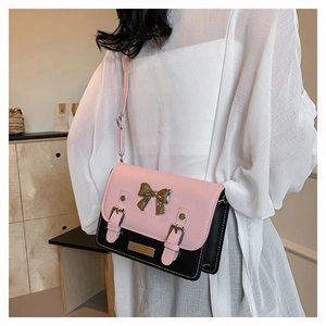 Detail view of pink and black contrast crossbody bag with bow hardware and straps