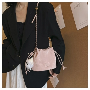 Borsa a secchiello rosa con coulisse, catena dorata e ciondolo a sfera in peluche bianco