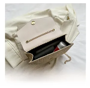 Detail view of the beige straw bag interior showing storage space and gold chain strap