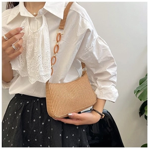 Detail of a khaki woven straw hobo bag with thick acrylic chain and broad shoulder strap