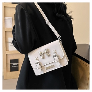 Detail of white envelope crossbody bag with silver bow and adjustable shoulder strap