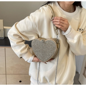Detail of sequined heart-shaped bag with silver chain strap and knotted leather handle