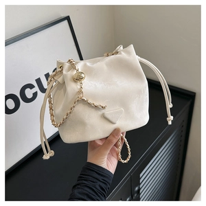 Dettaglio borsa a secchiello crema con coulisse, tracolla a catena e logo alla moda