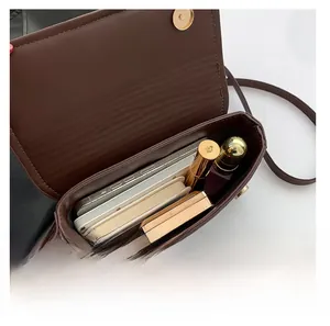 Macro detail of brown leather crossbody bag interior showing phone and lipsticks