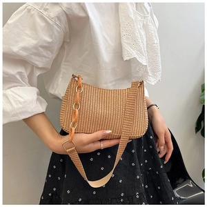 Detail of a beige woven hobo bag with an amber acrylic chain and shoulder strap on a model