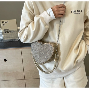 Macro shot of silver sequin heart bag with golden trim and metal chain strap details