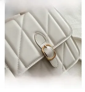 Close-up of white PU leather bag featuring V-shaped quilted texture and vintage gold buckle