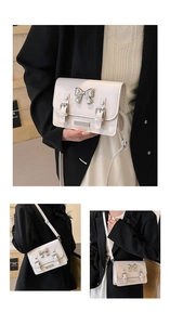 Detail of cream crossbody bag with silver bow accent and adjustable shoulder strap