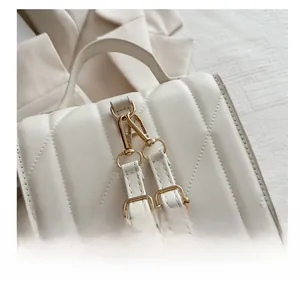 Detailed macro view of gold metal hooks and quilted V-pattern on the white leather bag