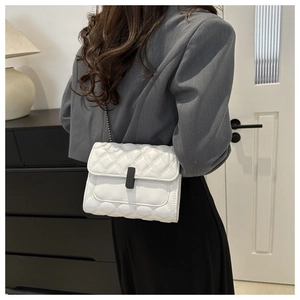 Detalle de bolso bandolera acolchado blanco con cierre negro mate y correa de cadena