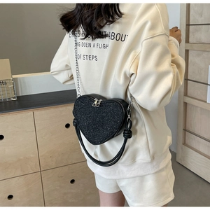 Detail view of heart-shaped sequin crossbody bag with chain strap and rope handle