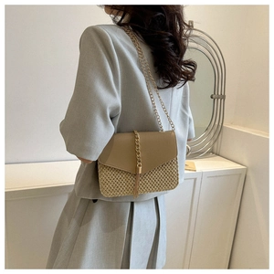 Close-up of khaki woven straw crossbody bag with gold chain tassels and leather flap