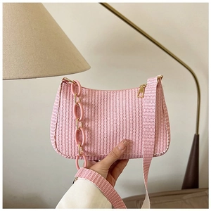 Detailed macro view of pink woven crescent bag with decorative chain and zipper detail