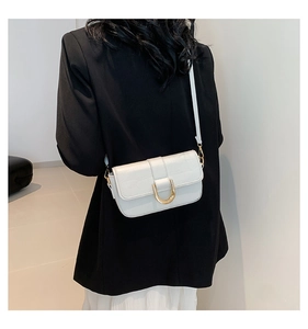 Detail of white crocodile pattern bag with gold horseshoe buckle on minimalist suit