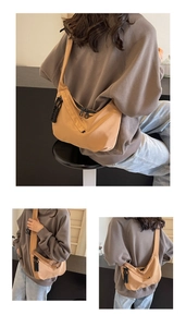 Detail view of khaki half-moon nylon bag with black double zippers and woven cord pullers