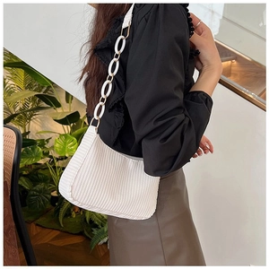 Detail view of white crescent bag with woven texture and resin chain strap on a model
