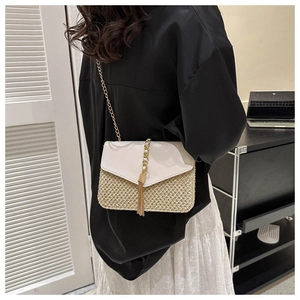 Detail of hand-woven straw crossbody bag with white leather flap and gold chain strap