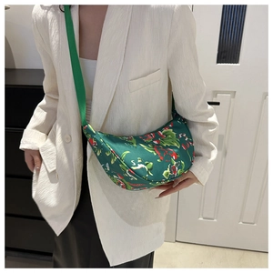 Detail of green floral crescent crossbody bag with red blossom pattern on white suit