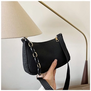 Detail of black woven crescent bag featuring a bold chunky black and gold chain strap